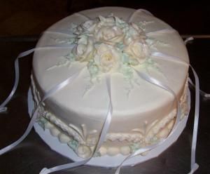 a wedding cake with white flowers and ribbons