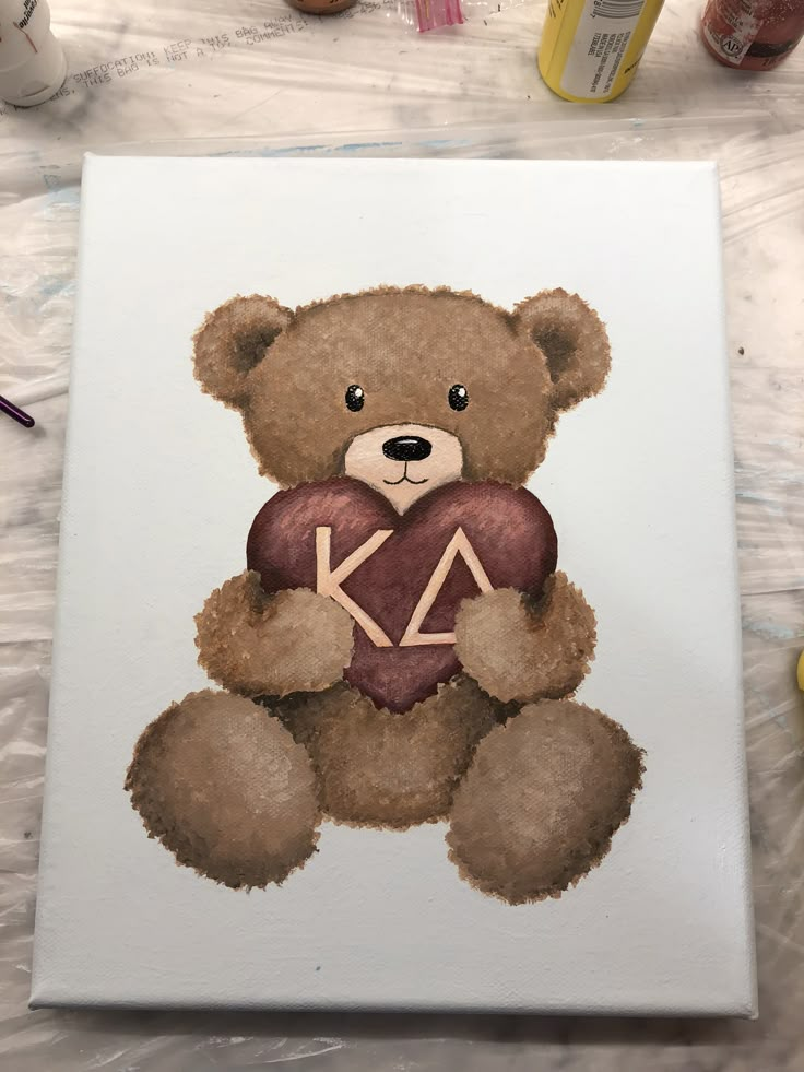 a painting of a teddy bear holding a heart with the letter k on it's chest