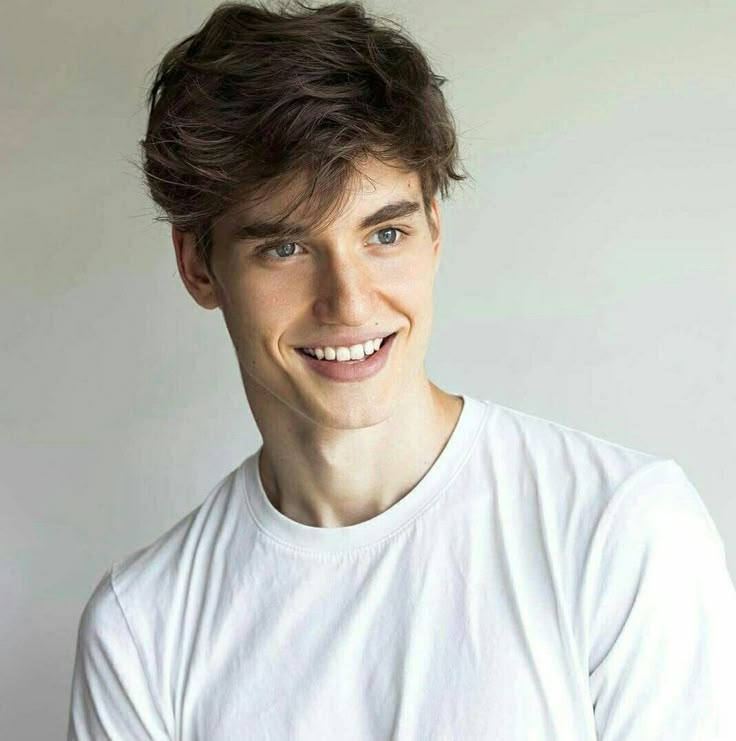 a smiling young man wearing a white t - shirt and looking at the camera with a smile on his face