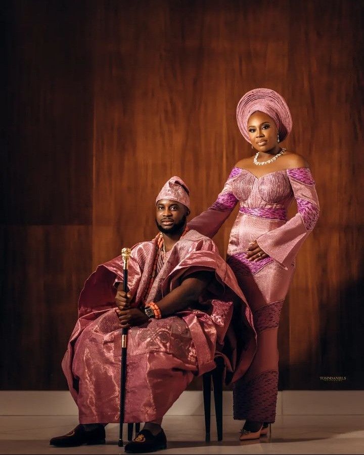 a man and woman in traditional african clothing pose for a photo together on a chair