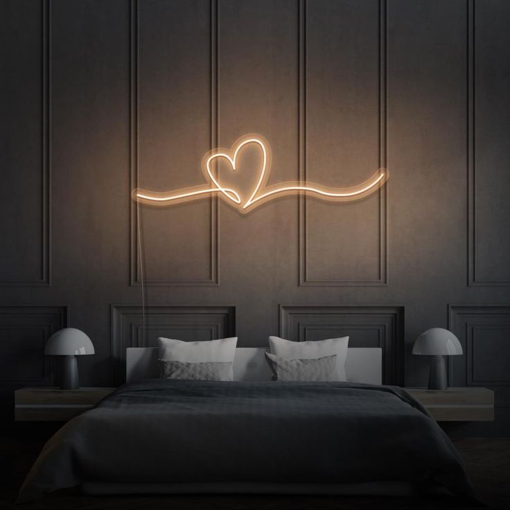 a bedroom with a bed, two lamps and a heart on the wall above it