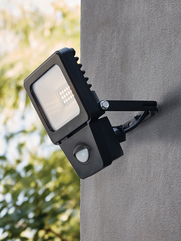 a close up of a light on the side of a building with trees in the background