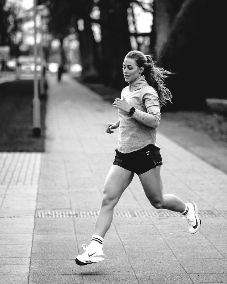 a woman running down a sidewalk in shorts