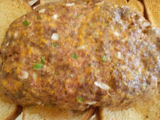 a sandwich with meat and cheese on it sitting on a plate next to some bread slices