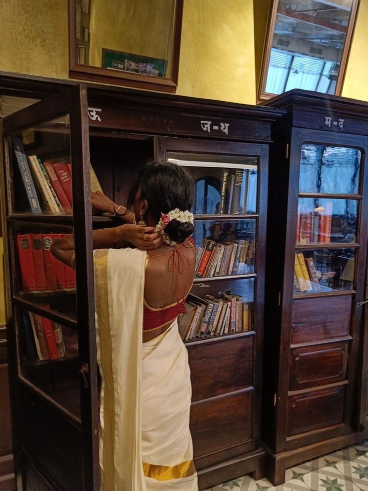 a woman standing in front of a book case with books on it's shelves