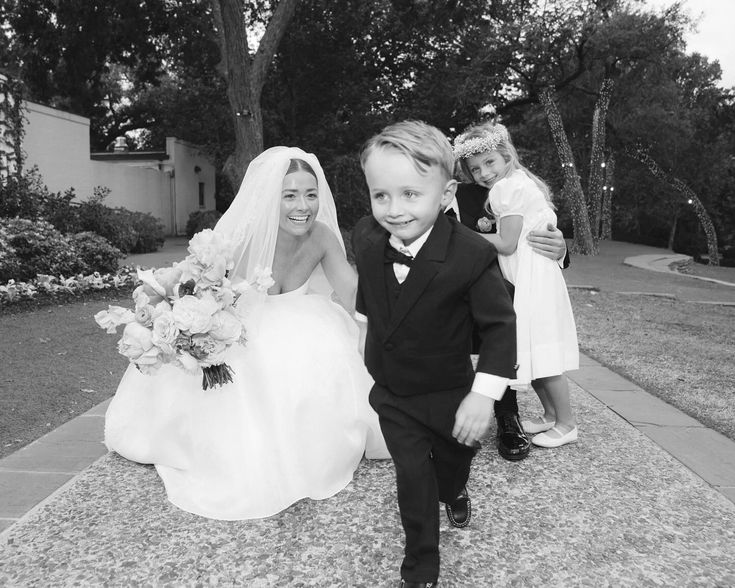 a young boy in a tuxedo walks down the aisle with his bride and flower girl