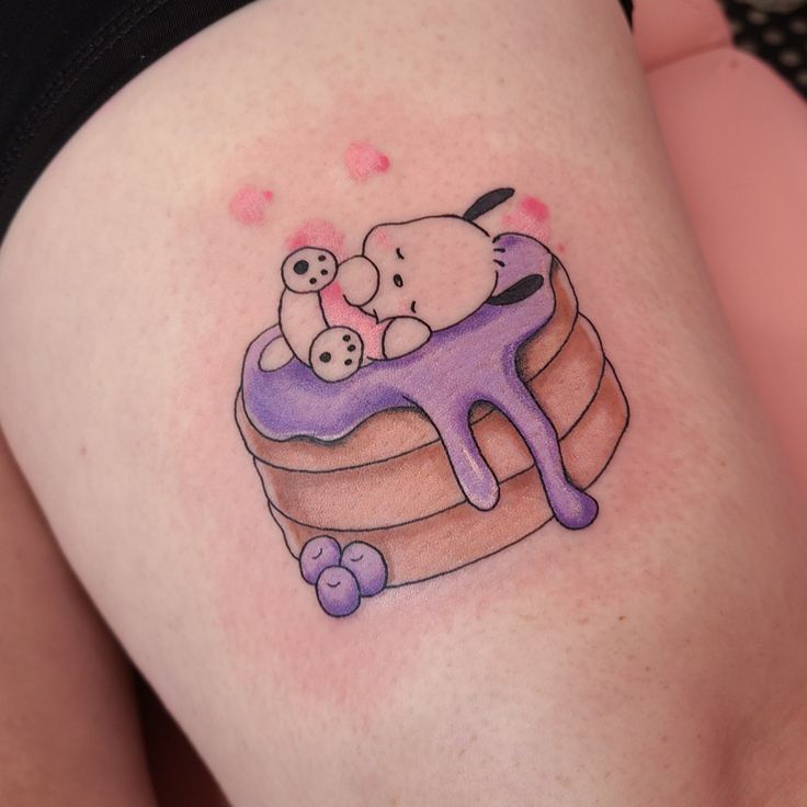 a woman's thigh with a tattoo of a dog and cat on top of a cake