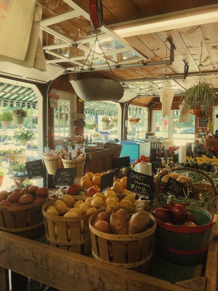 an open air market with lots of fruits and vegetables in buckets on the counter