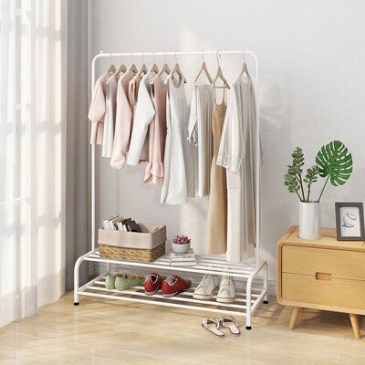 a white rack with shoes and clothes hanging on it next to a wooden dresser in front of a window