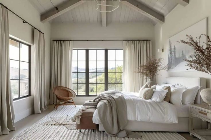 a bedroom with a large bed and two windows in it's side wall, along with an area rug on the floor