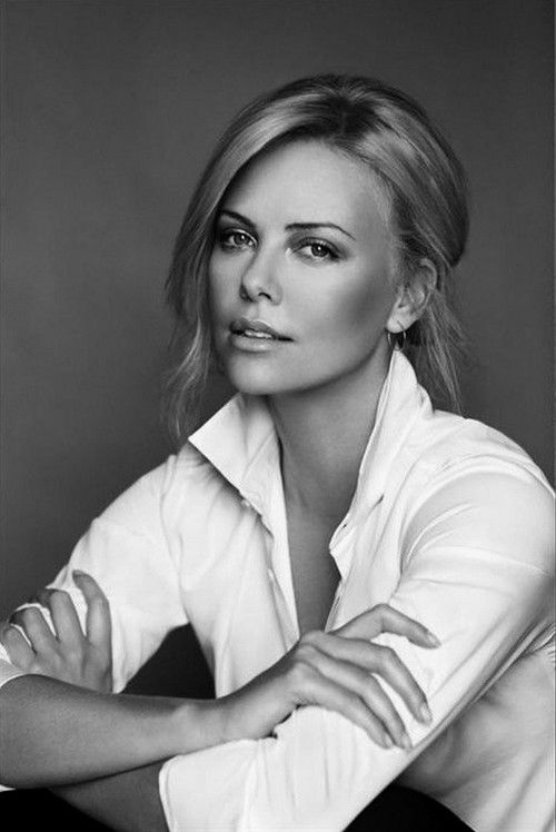 a black and white photo of a woman with her arms folded over her chest, looking at the camera