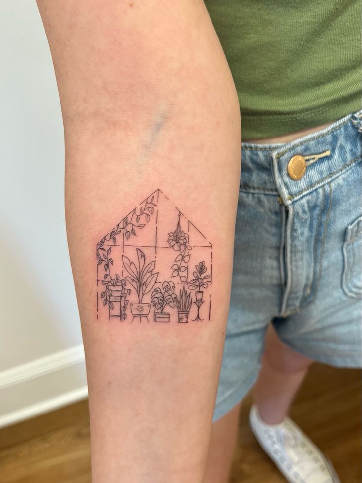 a woman with a tattoo on her arm showing the outline of a house and plants