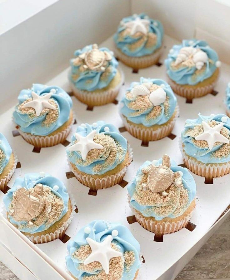 cupcakes with blue frosting and starfish on them in a white box