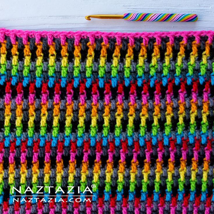 a crocheted blanket is shown with a knitting needle next to it and the colors of the yarn are multicolored