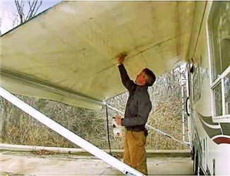 a man is painting the side of a bus with a white paint job on it