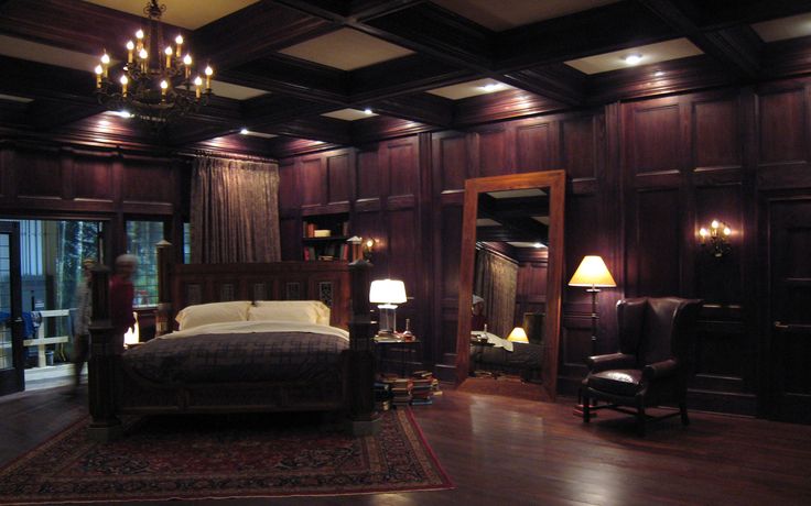 a large bedroom with wood paneling and chandelier