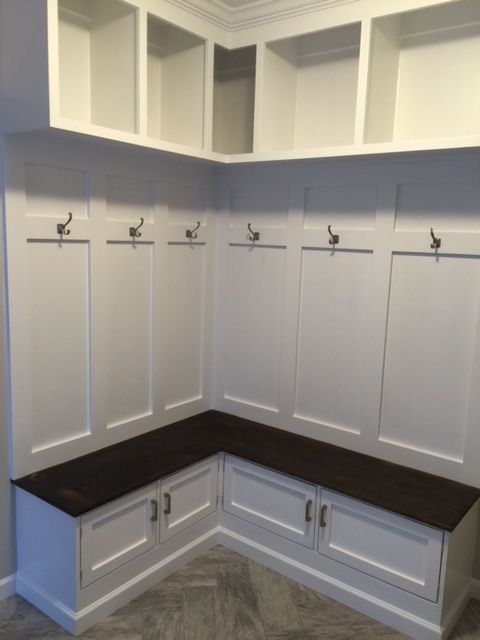 an empty white kitchen with wooden bench and cupboards on the wall above it is also built in cabinets