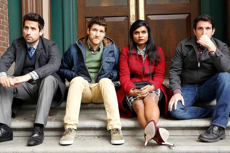 four people sitting on steps in front of a building