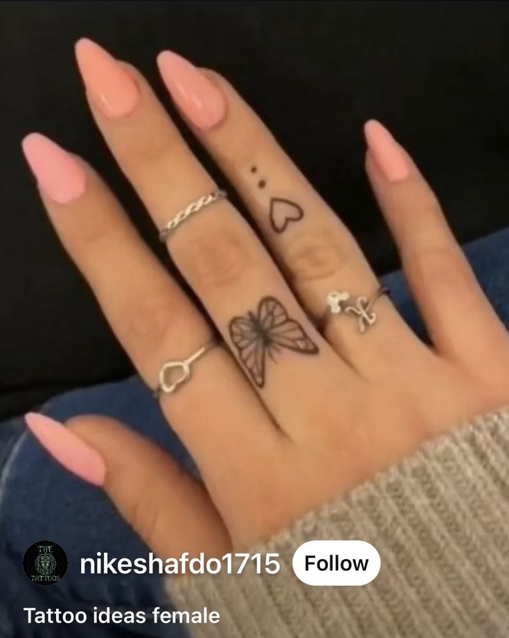 a woman's hand with four different tattoos on her fingers and two rings in the middle