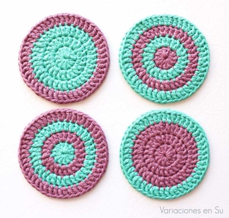 four crocheted coasters are shown on a white surface with green and pink circles