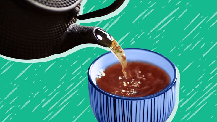 tea being poured into a blue cup on a green and white background with drops of water