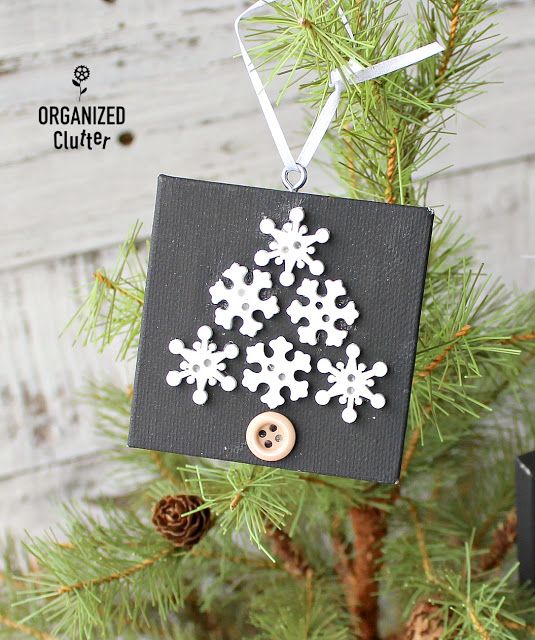 a christmas ornament hanging from a tree with snowflakes and buttons on it