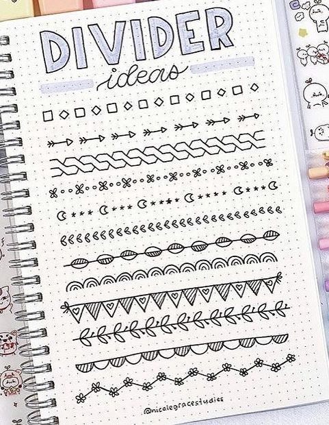 an open notebook with doodles and markers on it, next to some colored pencils