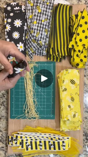 someone is cutting fabric with scissors on the table next to some flowers and other items