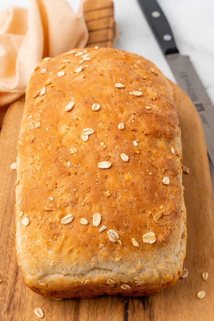 a loaf of bread sitting on top of a wooden cutting board next to a knife