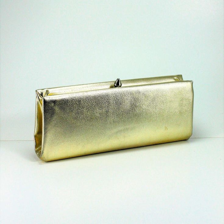 A classic bag that never goes out of style!  Sleek and simple gold lame' clutch handbag.  A gold tone snap closure, opens wide so you can get to your things!  Black vinyl lining.  Has a gold serpentine handle that tucks in when not in use.  Measures 10" long x 4 1/4".  In wonderful condition.  Perfect for a wedding, the holidays or anytime you want a bit of retro bling! International buyers welcome just contact me first for shipping charges. Gold Lame, Wedding Accessory, Style Formal, Classic Bags, Bridesmaid Wedding, Classic Gold, Mid Century Style, Black Vinyl, Vintage 60s