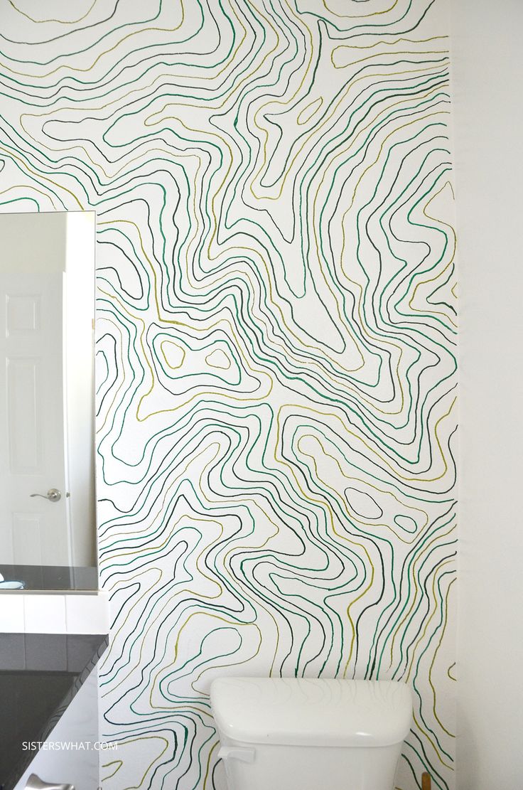 a white toilet sitting under a bathroom mirror next to a wall covered in wavy lines