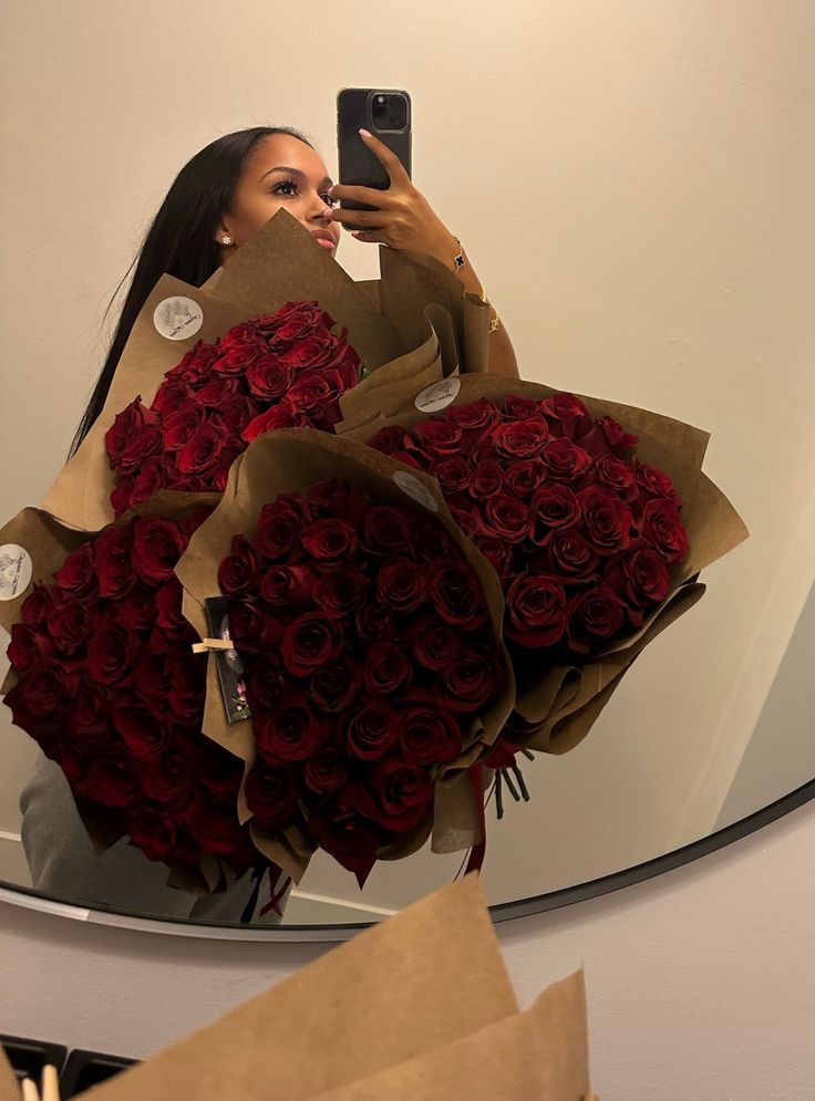 a woman taking a selfie in front of a mirror with roses wrapped around her