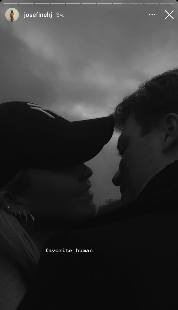 a man and woman standing next to each other in front of a dark cloudy sky