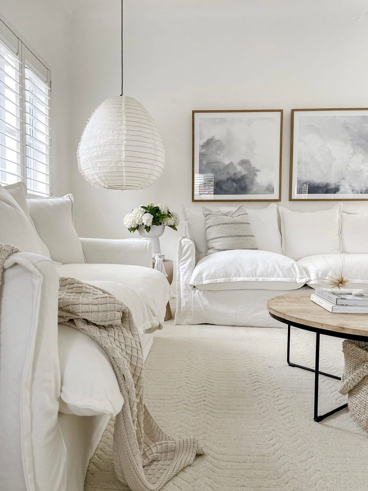 a living room filled with white furniture and decor on top of carpeted flooring