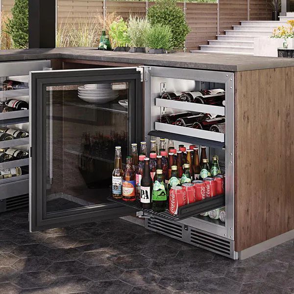 an open refrigerator with beer bottles in it on a patio next to a swimming pool