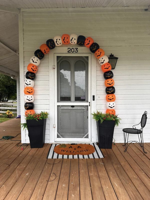 a front porch decorated for halloween with pumpkins and jack - o'- lanterns