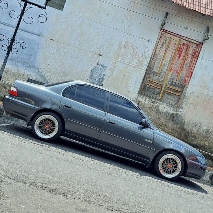 a grey car parked on the side of a road next to a building with an open door