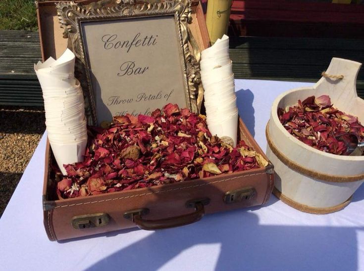 an open suitcase sitting on top of a table next to a bowl and cup filled with flowers