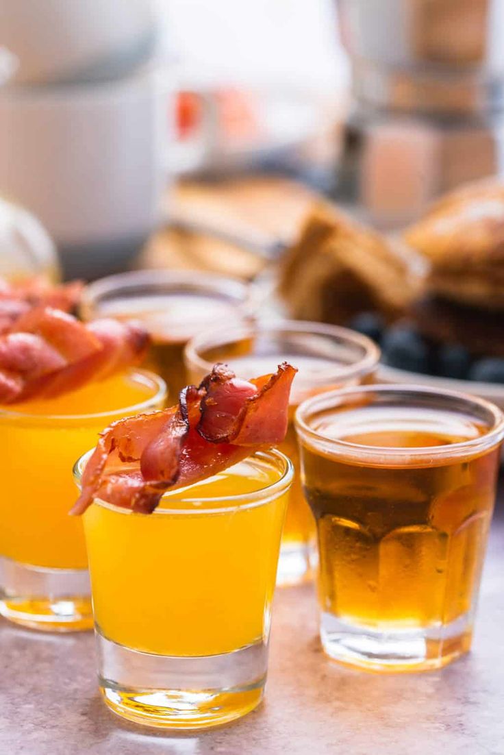 three glasses filled with drinks sitting on top of a table next to bread and other food