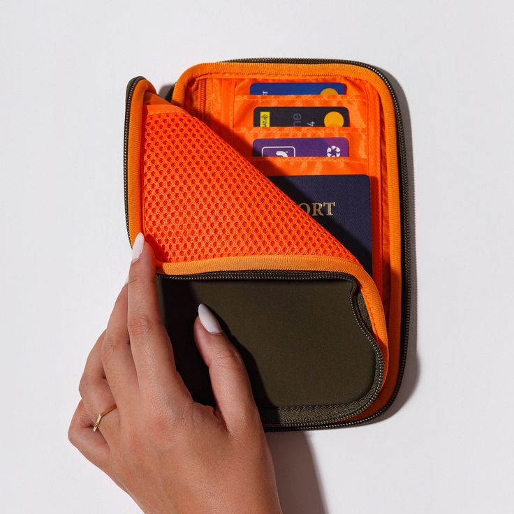 a woman's hand is holding an orange wallet