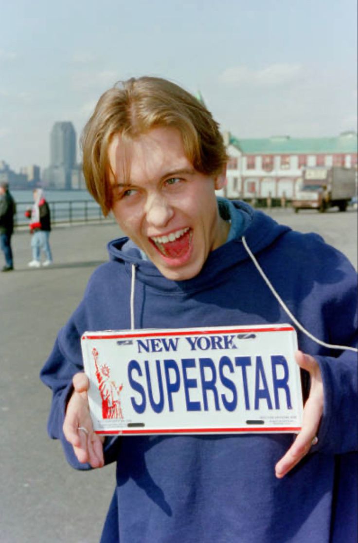 a young boy holding up a new york superstar license plate