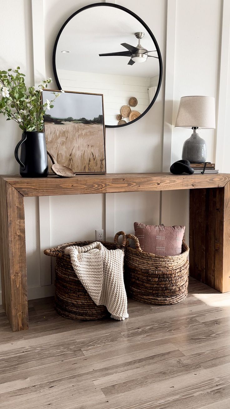 a wooden shelf with baskets underneath it and a mirror above the shelf next to it