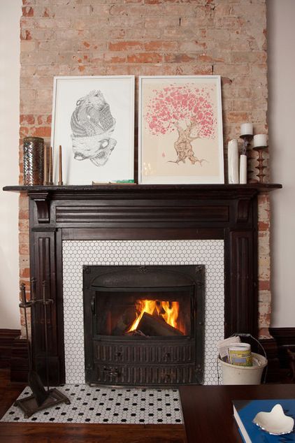 a fire place in a living room with pictures on the wall above it and an open fireplace