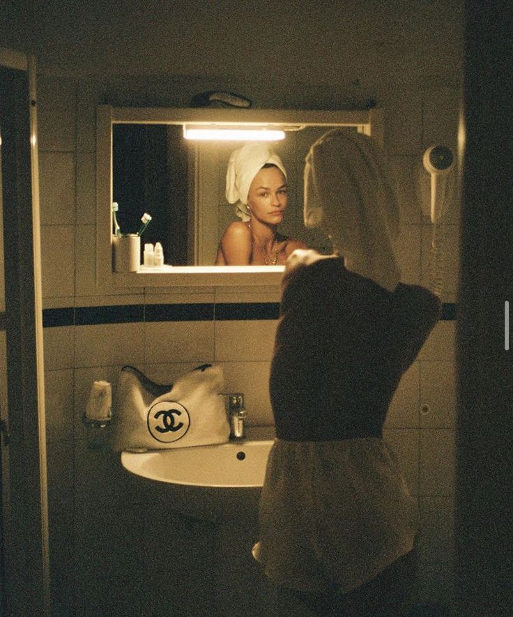 a woman standing in front of a bathroom mirror