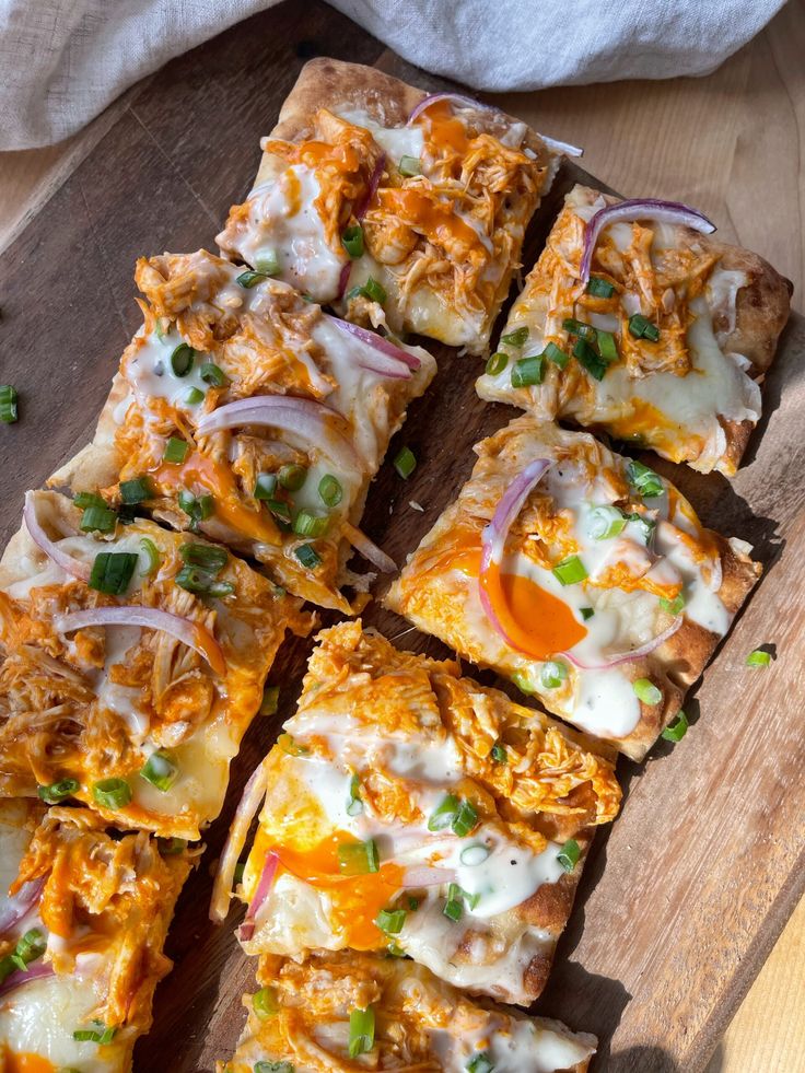 several slices of pizza on a cutting board with onions and cheese, sitting on a wooden surface