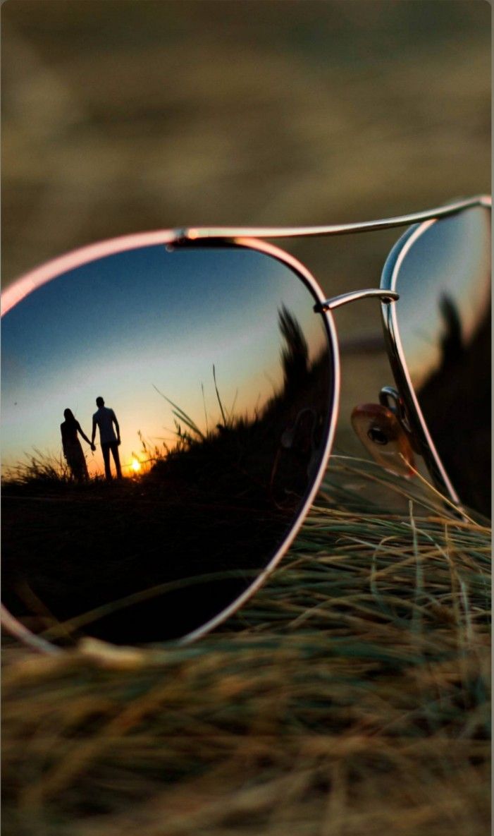 the reflection of two people in sunglasses is seen through the lens of another person's eye