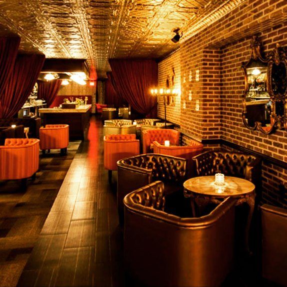 the interior of a restaurant with brick walls and red curtains on either side of the tables