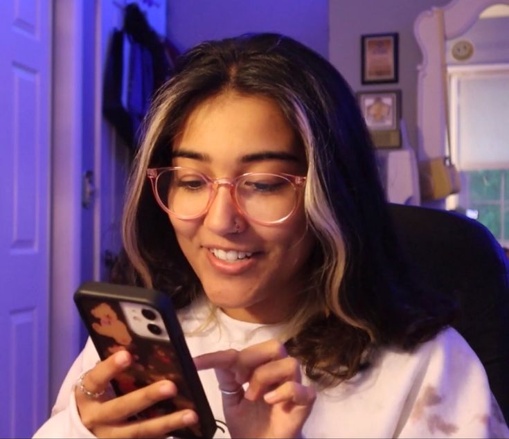 a woman wearing glasses looking at her cell phone