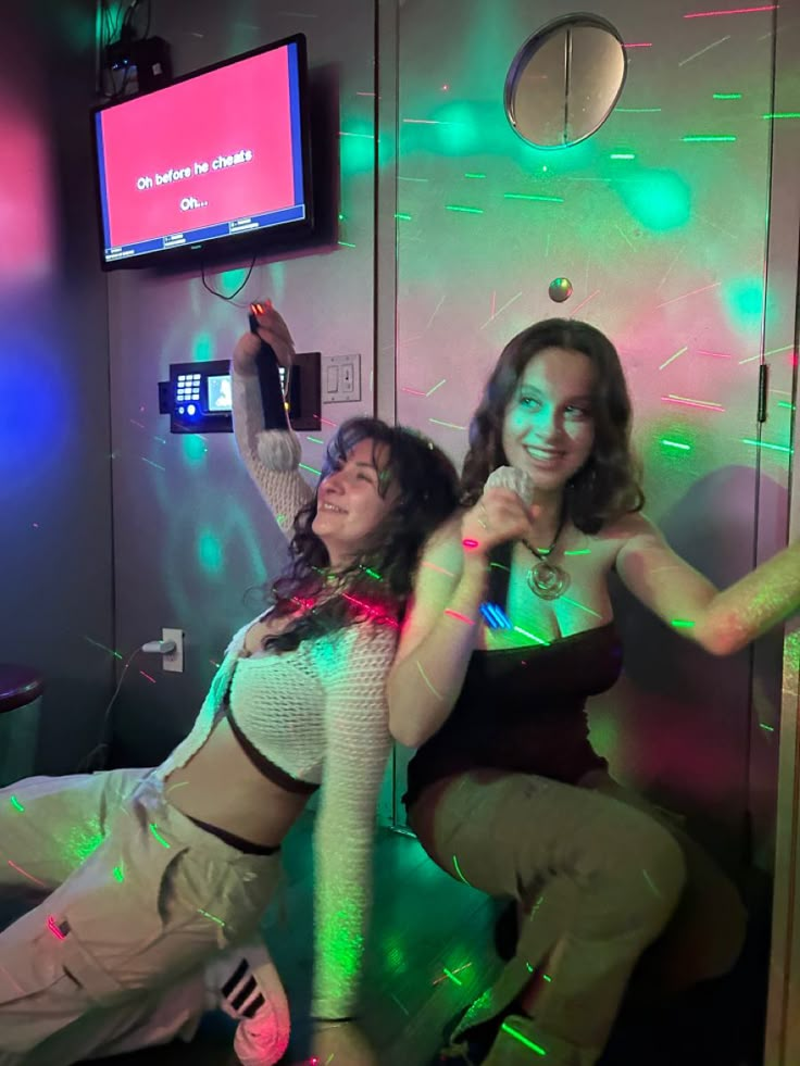 two women are posing for the camera in front of a mirror with green and pink lights