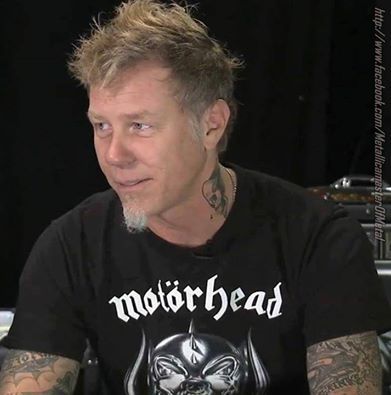 a man with tattoos sitting in front of a microphone